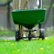 Man Pushing Spreader with Herbicides Across Lawn