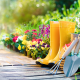 Colorful flower bed with yellow gardening boots, Features various lawn & garden tools.