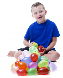 Boy with a pile of water balloons isolated on white background